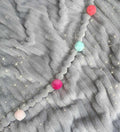 Cobija gris con pompones de colores